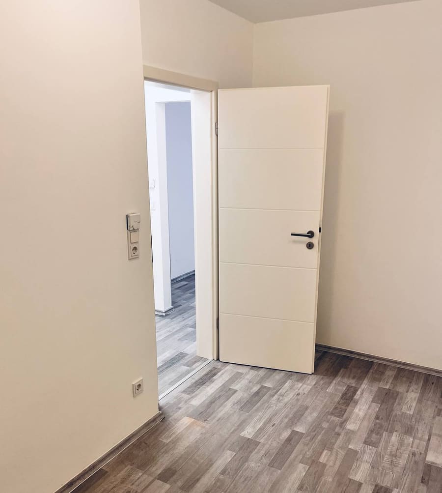 Fertiggestelltes Zimmer mit neuer Innentür und Bodenbelag in Holzoptik